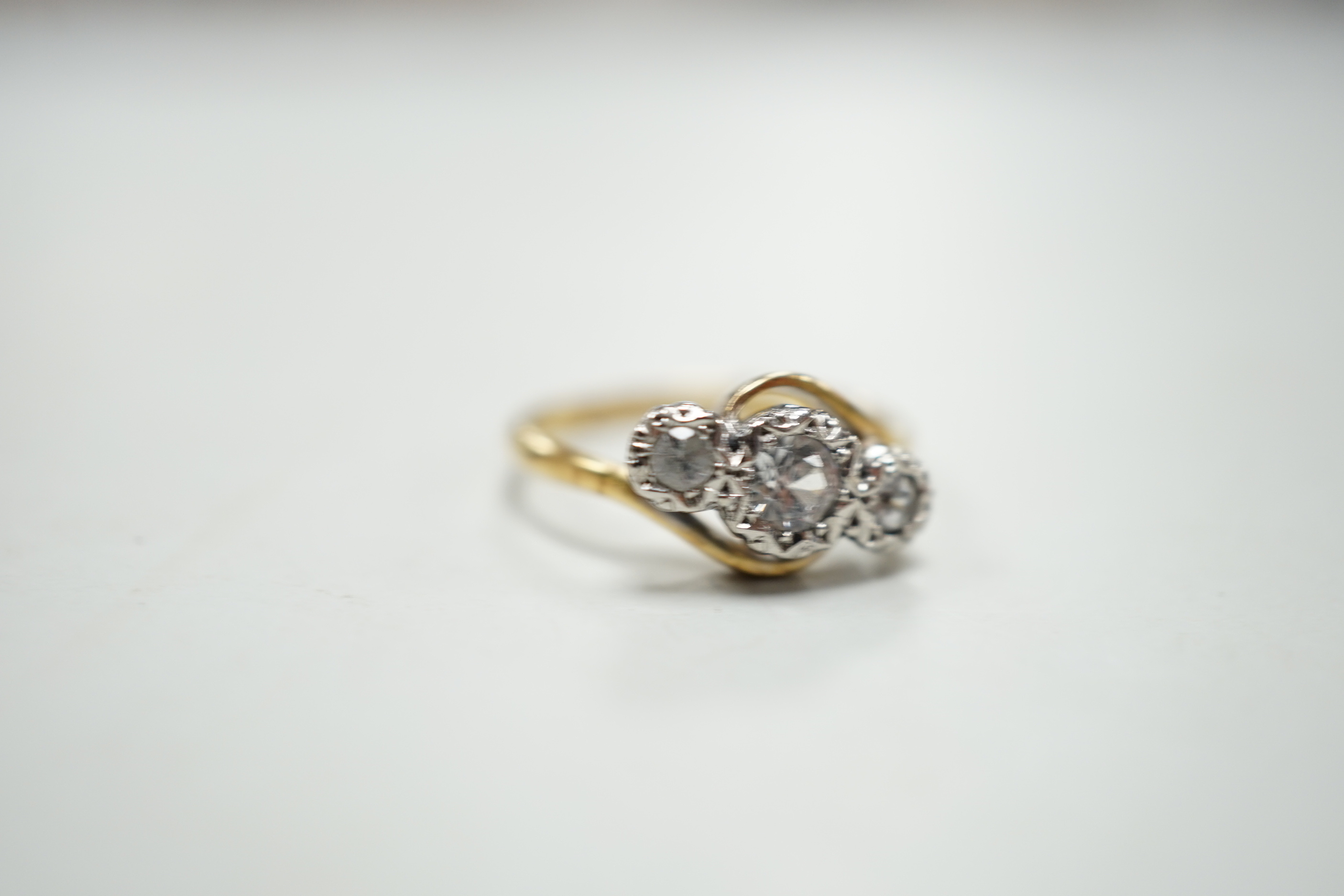 An 18ct and illusion set three stone diamond crossover ring, size I, gross weight 2.5 grams.